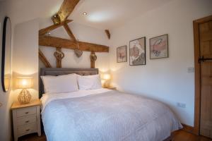 赫里福德Bramble Cottage - Cosy 2 Bed With Deluxe HOT TUB & Log Burner的一间卧室配有一张床和一张桌子上的两盏灯。