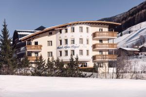 卡迪皮特拉Wellness Refugium & Resort Hotel Alpin Royal - Small Luxury Hotels of the World的一座白色的大建筑,在雪地里设有木制阳台