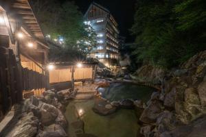 日光Nikko Nationalpark Kawamata Onsen KURA的一座建筑前的岩石水池