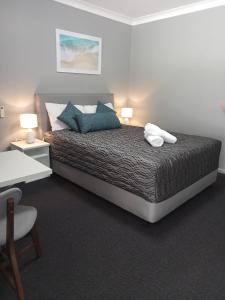 卧龙岗Solomon Inn Motel Figtree的一间卧室配有一张带蓝色枕头的床