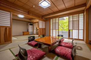 日光Nikko Nationalpark Kawamata Onsen KURA的客厅配有木桌和红色靠垫