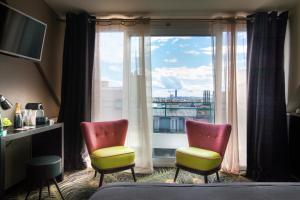 巴黎赫鲁斯酒店的客房设有两把椅子和大窗户