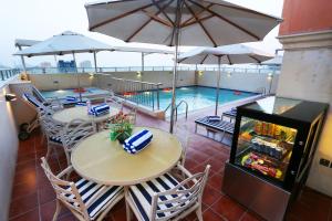 沙迦Al Hamra Hotel的一个带桌子和遮阳伞的庭院和一个游泳池