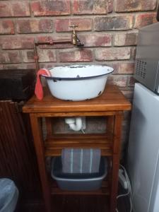 奥茨胡恩Earthbound Guest House的木桌上的白色碗,带水槽