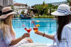 索佐波尔Cristiani Hotel Sozopol的两名妇女在游泳池前喝鸡尾酒