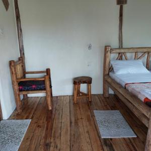 KatunguruSongbird Safari Lodge & Campsite的一间卧室配有一张床和一把椅子,铺有木地板