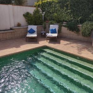 格拉纳达Villa 28 de julio Casa Rural con piscina en Granada的游泳池旁的两把椅子