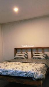 PlambiTiara Homestay的卧室配有一张挂有墙上标志的床
