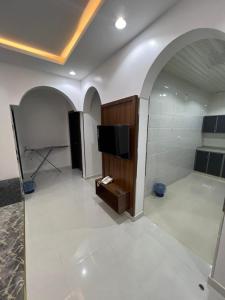 奈季兰شقق برج السمو للشقق المفروشة的带电视的客厅和铺有白色瓷砖的房间。