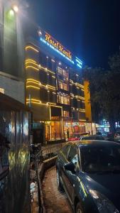 西里古里Hotel Manila的夜间停在大楼前的汽车