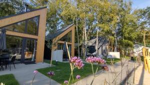 梅尔诺Village Mielno - najpiękniejsze domki wakacyjne nad morzem的院子中带玻璃门和紫色花朵的房子
