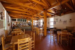 BacáicoaKampaoh Sierra de Urbasa的一间带木桌椅的餐厅和一间酒吧