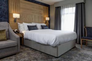 诺丁汉华美达诺丁汉市中心酒店的一间卧室设有一张大床、一把椅子和窗户。