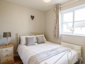 TiptreeCherry Blossom Place的一间卧室配有一张带白色床单的床和一扇窗户。