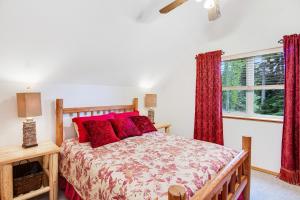 麦考尔Cedar House的一间卧室配有一张带红色枕头的床和一扇窗户