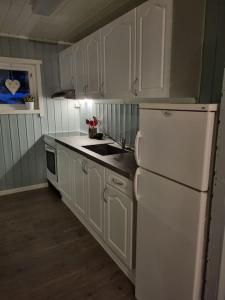 BrygghaugenOff-the-grid cabin on the island of Senja in northern Norway的厨房配有白色橱柜和白色冰箱。