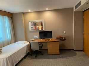 圣保罗Ibirapuera hotel 5 estrelas 2 suites的一间卧室配有一张桌子,里面装有电脑