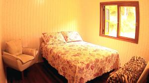 南卡希亚斯Cabana das Montanhas的卧室配有床、椅子和窗户。