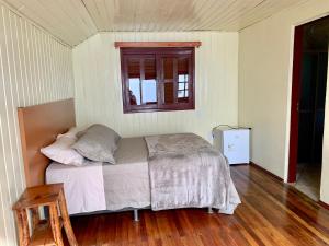 坎巴拉Central Chalés的一间卧室设有一张床和一个窗户,铺有木地板