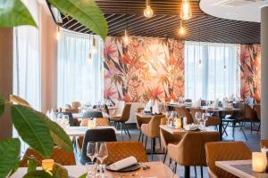 美因河畔法兰克福Best Western Hotel Airport Frankfurt的一间设有桌椅的餐厅,种植了植物