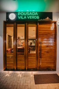 维索萨-杜塞阿拉Pousada Vila Verde的商店前有木门和标志