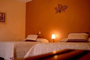 HuichapanVillas San Francisco的一间卧室设有两张床,墙上配有一盏灯。