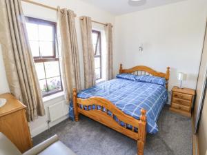巴利萨代尔Belladrihid Cottage的一间卧室设有木床和2个窗户。