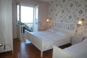 伯德古拉Apartments by the sea Podgora, Makarska - 12465的一间白色卧室,配有两张床和窗户