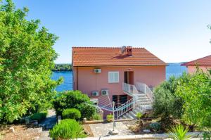 普利兹巴Apartments by the sea Karbuni, Korcula - 13217的水前有楼梯的粉红色房子