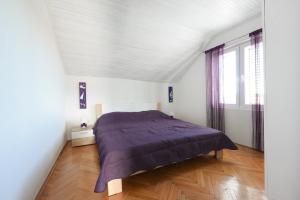 扎达尔Apartments with a parking space Zadar - 13534的一间卧室配有一张带紫色毯子的床
