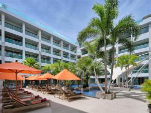 芭东海滩The Kee Resort & Spa的一个带椅子和遮阳伞的酒店和一个游泳池