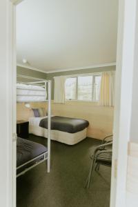 怀托摩洞穴Waitomo Village Chalets home of Kiwipaka的带两张双层床和椅子的房间