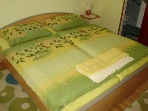 Kneževi VinogradiRooms with a parking space Knezevi Vinogradi, Baranja - 15024的一张带绿棉被的床,上面有一条毛巾