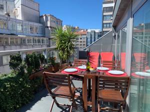 拉科鲁尼亚Penthouse with terrace and views near Oza's beach的公寓阳台的木桌和椅子