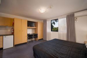 悉尼Drummoyne Furnished Apartments的酒店客房配有一张床、一张书桌和一间厨房。