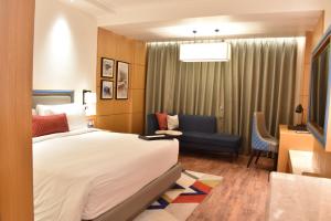 格德拉Ramada by Wyndham Katra Station Road的配有一张床和一把椅子的酒店客房