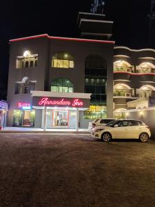 SeonīAnnandam Inn(Hotel Anand)的夜间停在大楼前的白色汽车