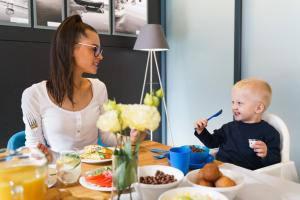 格但斯克金郁金香格但斯克公寓酒店的坐在桌子上吃食物的女人和婴儿