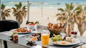 特拉维夫特拉维夫海滩皇冠假日酒店的一张带早餐食品的桌子,享有海滩美景