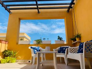 卡拉费尔安静度假屋 - 距离海滩5英尺的天井设有白色椅子和黄色墙壁上的桌子