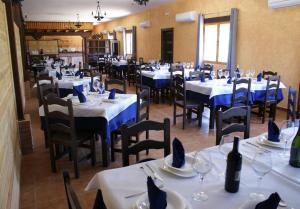 Navas de EstenaKampaoh Cabañeros的餐厅配有白色的桌椅和蓝色的餐巾