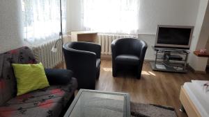 库罗阿尔滕堡Ferienwohnung Schaarschmidt的客厅配有沙发、两把椅子和电视