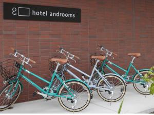 札幌hotel androoms Sapporo Susukino的三辆自行车停在砖墙旁边
