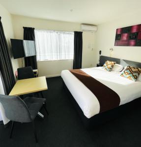 基督城298西区汽车旅馆的酒店客房设有一张大床和一张书桌。