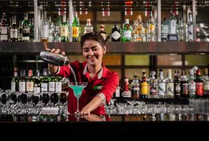 曼谷Holiday Inn Bangkok Silom, an IHG Hotel的站在酒吧后面喝着饮料的女人