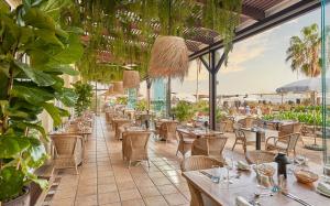丰沙尔Hotel Porto Santa Maria - PortoBay - Adults Only的一间设有桌椅的餐厅,种植了植物