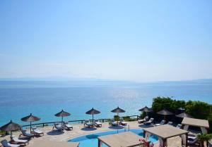 阿菲托斯Blue Bay Halkidiki的毗邻大海的带椅子和遮阳伞的游泳池
