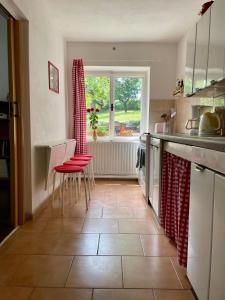 Horní PoliceSilver Linden Cottage的厨房配有红色的椅子和桌子,设有窗户