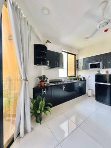 胡鲁马累BODU ASHI MALDIVES - Central 3 Bedroom Apartment的一间厨房,配有黑色橱柜和大窗户