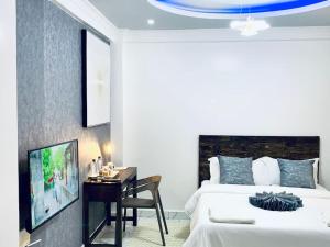 纳纽基Arabel Studio Apartment的一间卧室配有一张床、一张书桌和一台电视